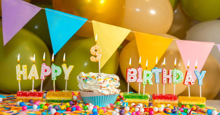 A close-up of a birthday cake with candles that spell out "HAPPY BIRTHDAY" and a number 9 candle in the center. The cake is decorated with colorful sprinkles and surrounded by party decorations.