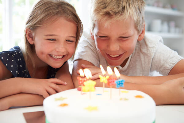 Kids joyfully celebrating a birthday with a cake, capturing the excitement and festivities of the moment.