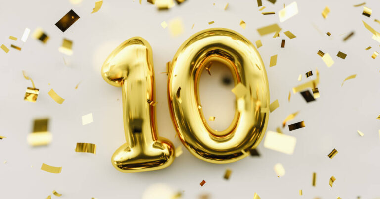 Gold balloons in the number '10', with gold confetti sprinkled on a table.