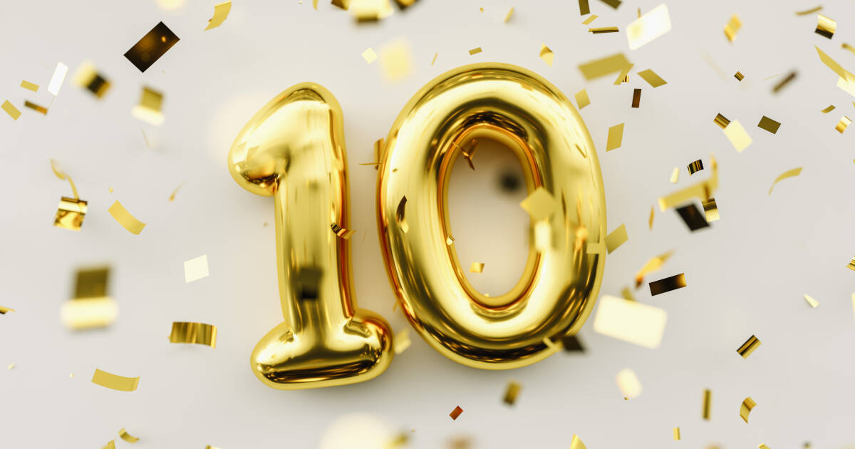 Gold balloons in the number '10', with gold confetti sprinkled on a table.