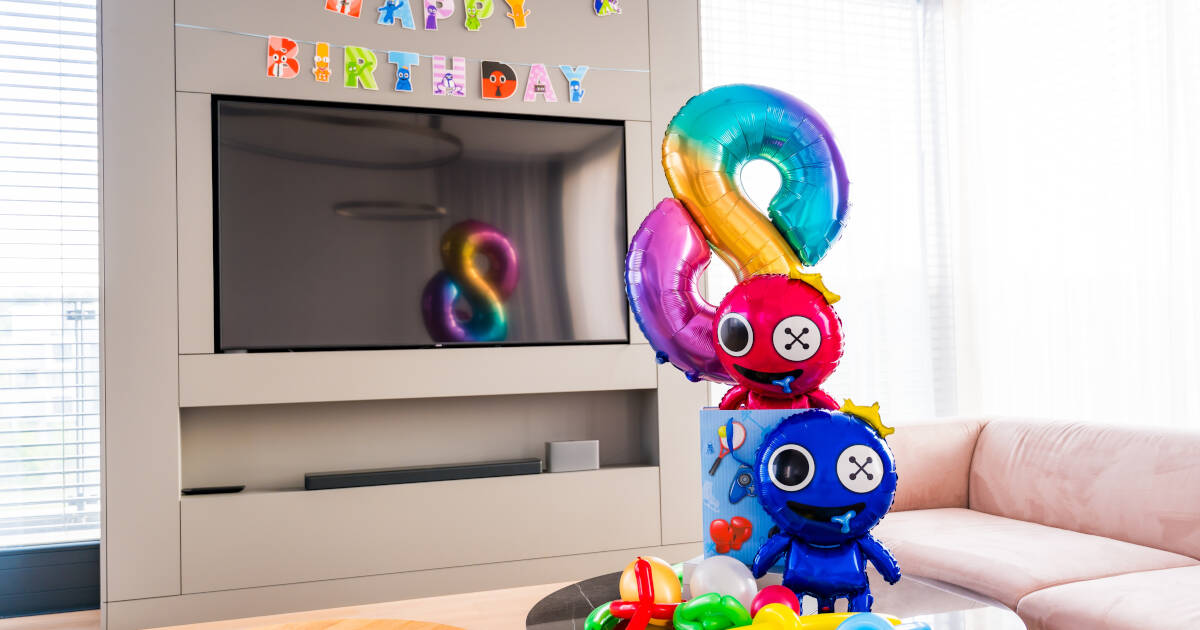 Colorful "Happy Birthday" banner above a TV, with rainbow number 8 balloon and fun character balloons in a living room.