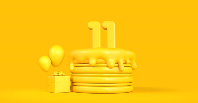 Yellow cake with number 11 candles, three balloons, and a gift box on a slid yellow background.