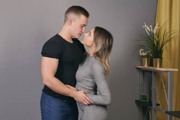 A 22-year-old couple embraces at home, gazing into each other's eyes.