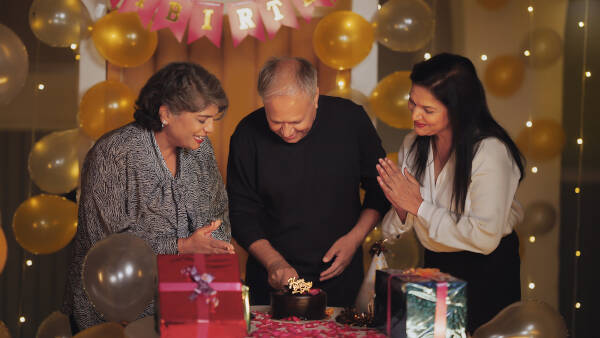 A family celebrating a birthday, gathered around a cake with warm lighting and festive decorations.