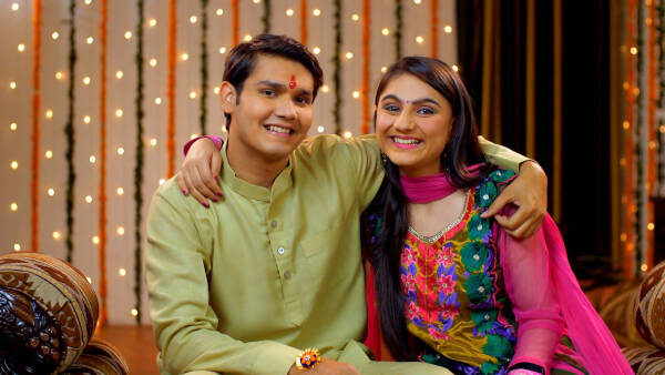 Brother and sister put their arms around each other and pose for a photo, smiling.