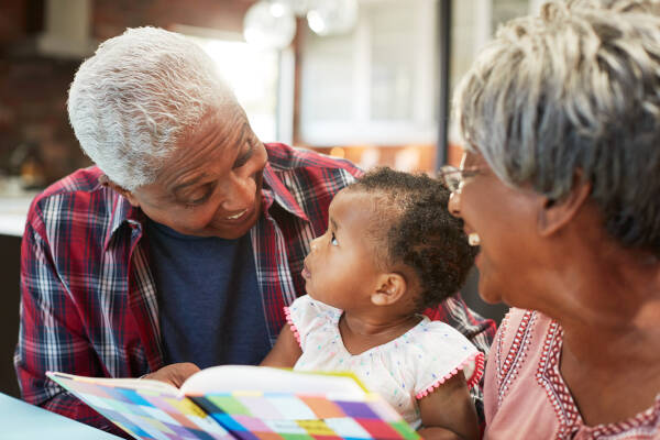 Captured in a cozy home setting, grandparents lovingly engage with their baby granddaughter.