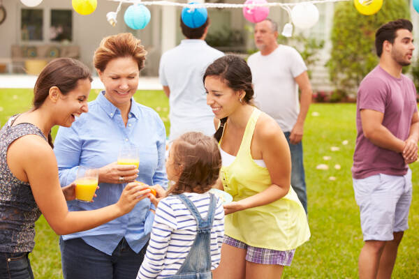 Group of women and children enjoying drinks and laughing together at a backyard outdoor gathering.