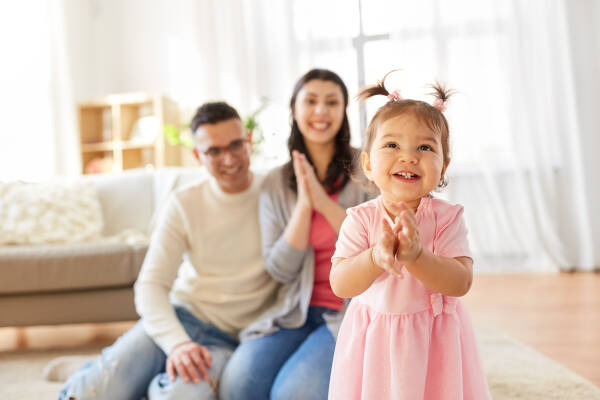 Happy little daughter smiles with mother and father at home, all beaming with joy.