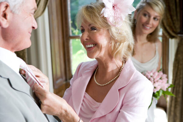 Senior couple looking into each other's eyes about to get married, with the woman's daughter in the background looking on happily.