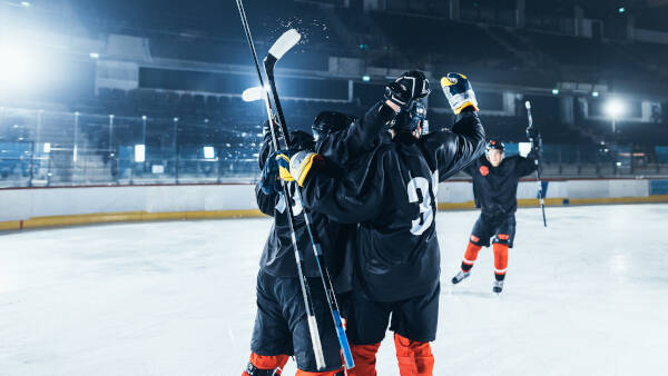 A group of ice hockey players huddling together on the rink, celebrating a victory under the arena lights.