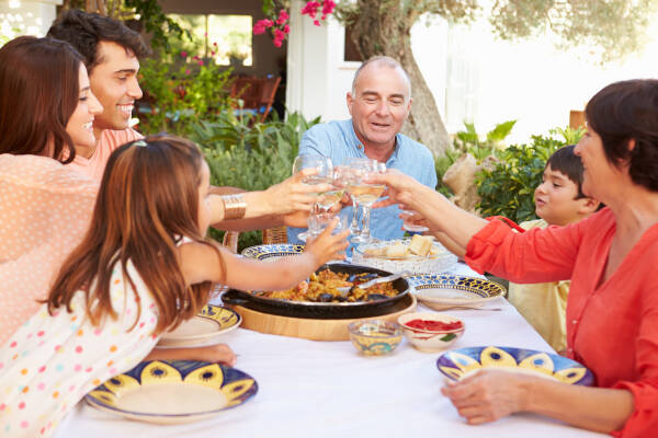 Family raising glasses for a toast while enjoying a meal outdoors.